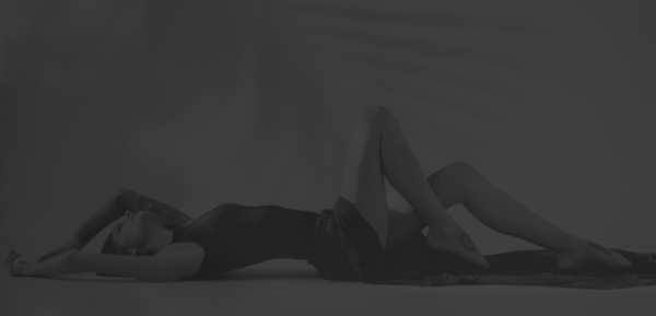 Women's Sexual Wellness. Black and white image of woman laying on the ground in a black dress.
